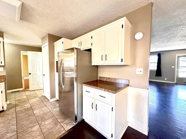 kitchen featuring white cabinetry, a textured ceiling, and freestanding refrigerator