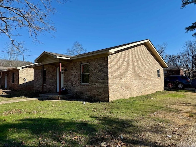 view of home's exterior featuring brick siding and a yard