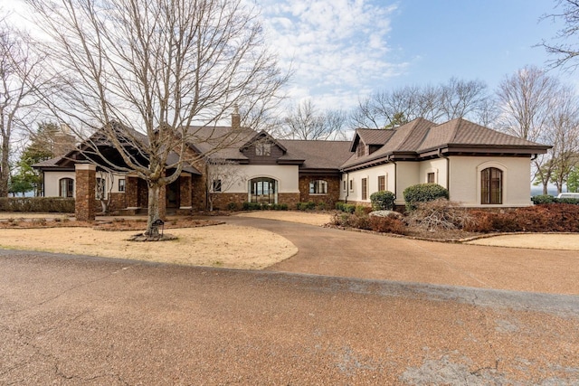 view of front of house with driveway, a chimney, and stucco siding