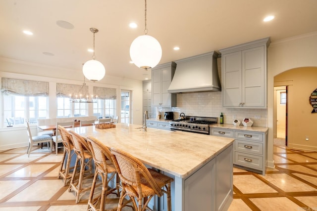 kitchen with high end stainless steel range oven, baseboards, custom exhaust hood, and gray cabinetry