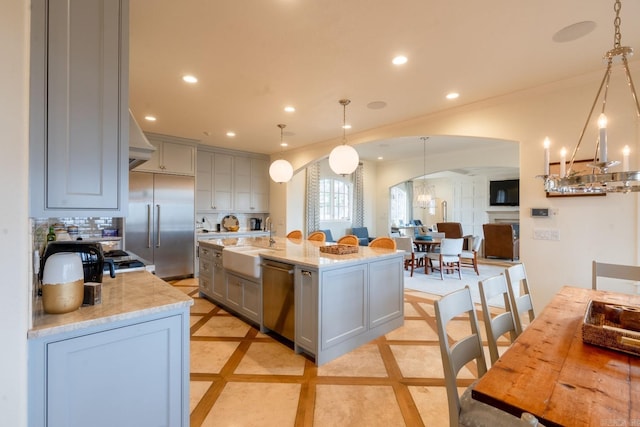 kitchen featuring arched walkways, recessed lighting, stainless steel appliances, a sink, and gray cabinets