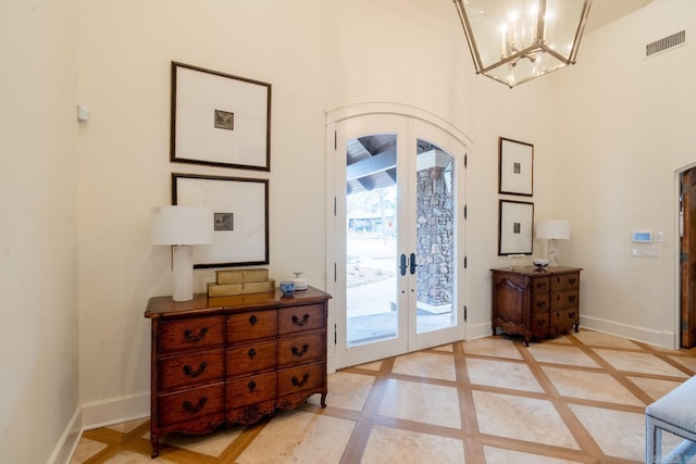 doorway to outside featuring arched walkways, french doors, visible vents, an inviting chandelier, and baseboards