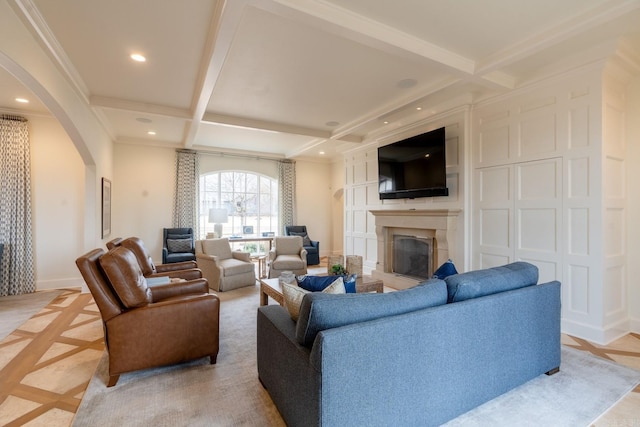 living room featuring arched walkways, coffered ceiling, a glass covered fireplace, beam ceiling, and recessed lighting