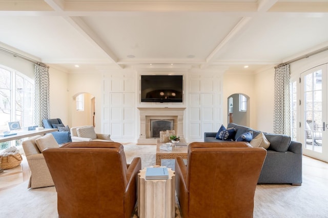 living area with a fireplace with raised hearth, arched walkways, coffered ceiling, and beamed ceiling