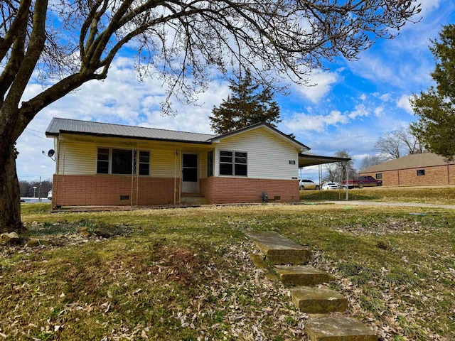 view of front facade with metal roof, an attached carport, crawl space, a front lawn, and brick siding