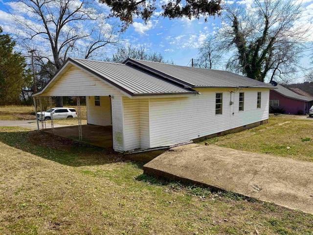 view of home's exterior with a standing seam roof, metal roof, a carport, and a lawn