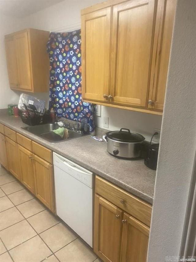 kitchen with white dishwasher, a sink, and light tile patterned flooring