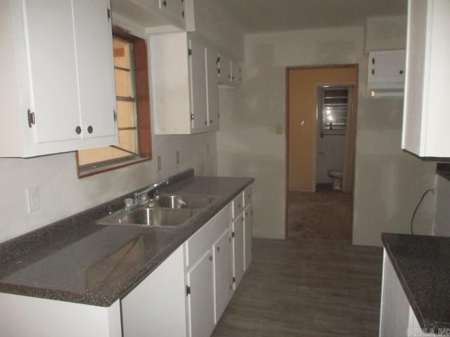 kitchen featuring dark wood-style floors, dark countertops, white cabinetry, and a sink