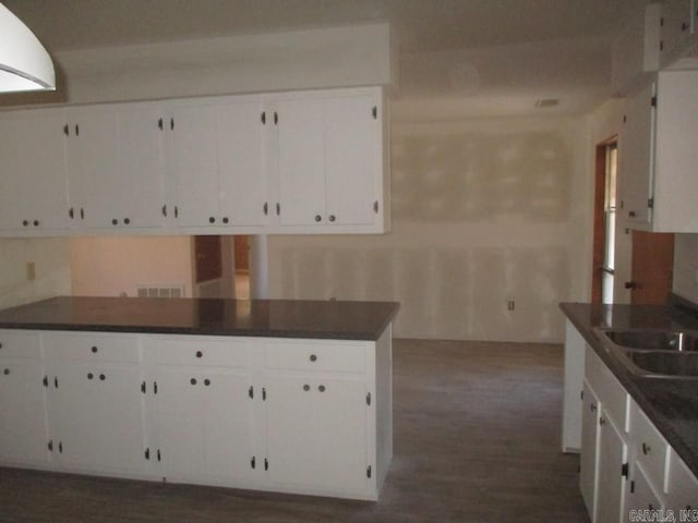 kitchen with dark countertops, white cabinets, and a sink