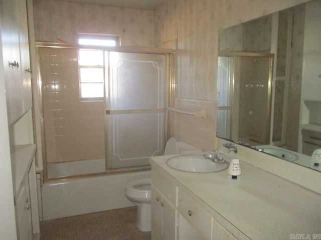 bathroom featuring toilet, shower / bath combination with glass door, tile walls, and vanity