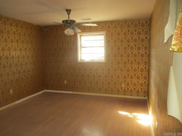 spare room with wallpapered walls, a ceiling fan, baseboards, and wood finished floors