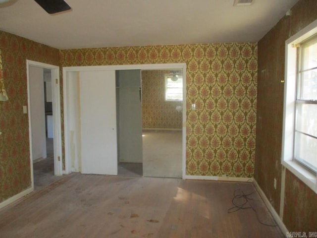 spare room with wood finished floors, visible vents, baseboards, and wallpapered walls