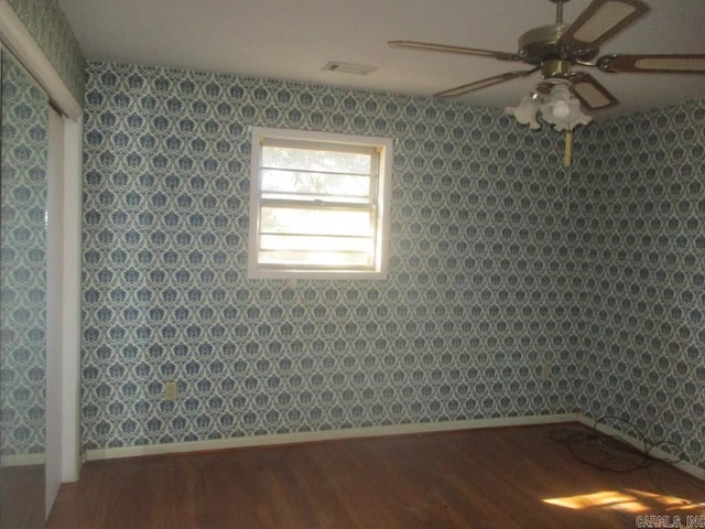 spare room featuring baseboards, wood finished floors, a ceiling fan, and wallpapered walls