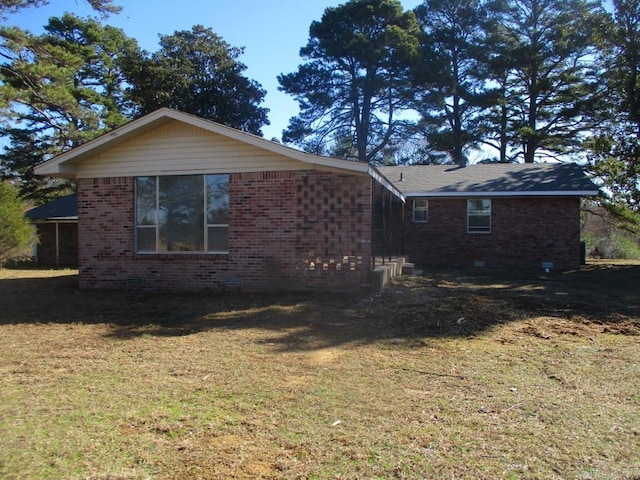 view of home's exterior with crawl space, brick siding, and a lawn