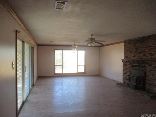 unfurnished living room featuring a ceiling fan, visible vents, crown molding, and a textured ceiling