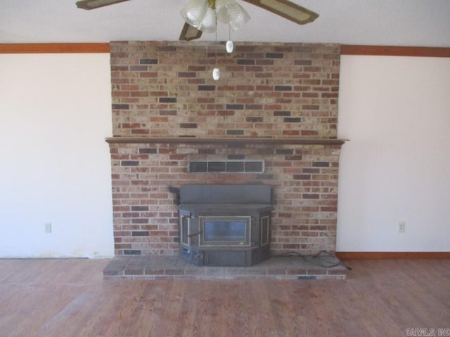 room details with wood finished floors, visible vents, baseboards, a ceiling fan, and a wood stove