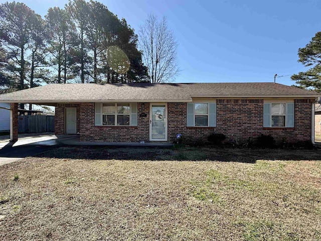 ranch-style home featuring brick siding, driveway, roof with shingles, a carport, and a front yard