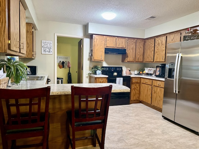 kitchen featuring visible vents, stainless steel fridge with ice dispenser, brown cabinets, a peninsula, and black range with electric cooktop