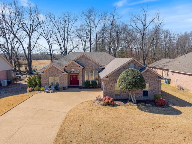 view of front facade with driveway, a front yard, and brick siding