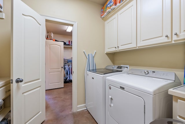 laundry area featuring cabinet space, dark tile patterned floors, and separate washer and dryer