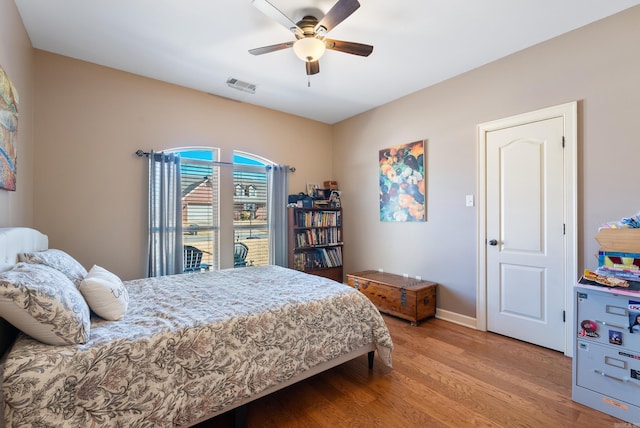 bedroom featuring baseboards, wood finished floors, visible vents, and a ceiling fan