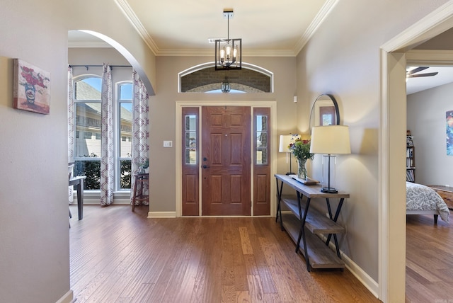 foyer entrance with ornamental molding, wood finished floors, and baseboards