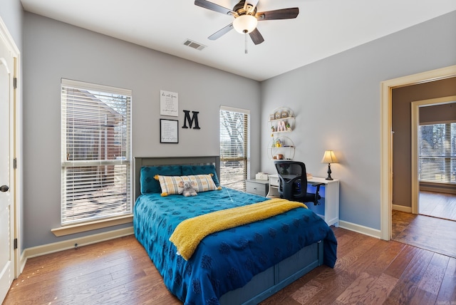 bedroom with hardwood / wood-style floors, multiple windows, visible vents, and baseboards