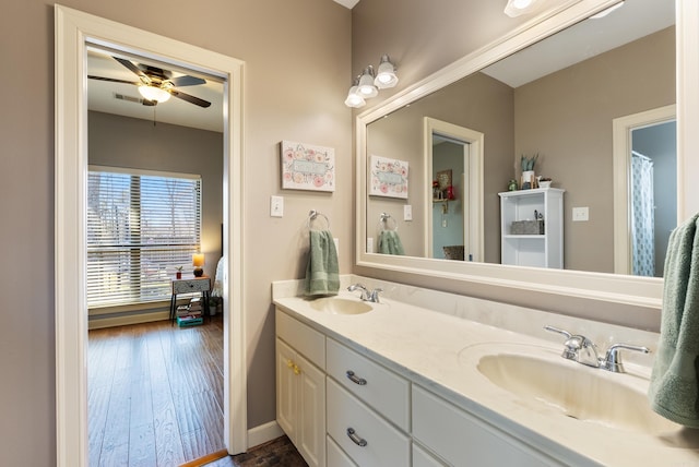 bathroom featuring ceiling fan, double vanity, wood finished floors, and a sink