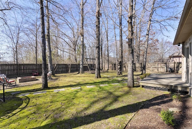 view of yard with a fenced backyard, a fire pit, and a wooden deck