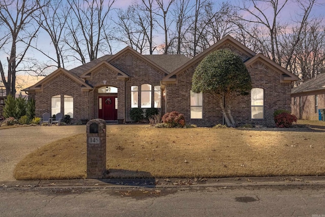 view of front of house with brick siding and a front lawn