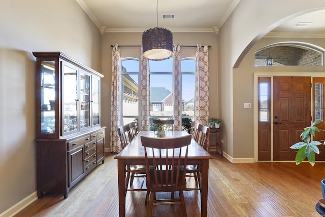 dining area featuring ornamental molding, light wood-type flooring, visible vents, and baseboards