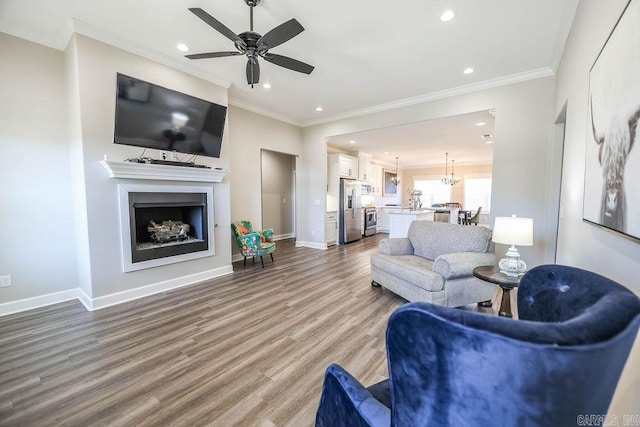 living room with ornamental molding, a fireplace, baseboards, and wood finished floors