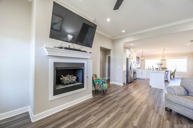 living room with baseboards, dark wood-type flooring, crown molding, and a chandelier