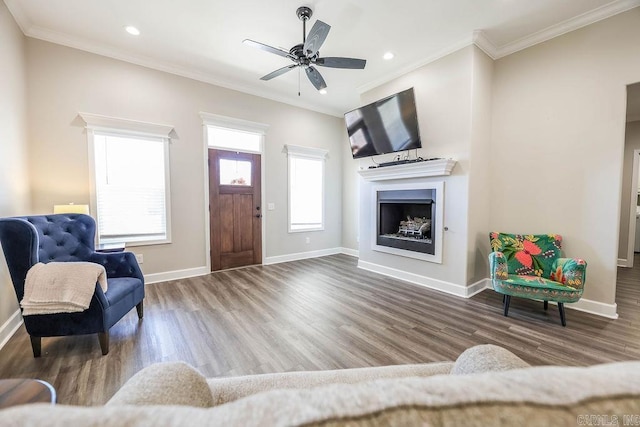 living room featuring ornamental molding, a fireplace, baseboards, and wood finished floors