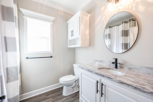 bathroom featuring crown molding, toilet, vanity, wood finished floors, and baseboards