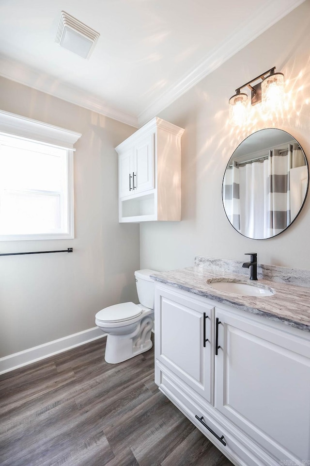 bathroom featuring visible vents, ornamental molding, vanity, wood finished floors, and baseboards