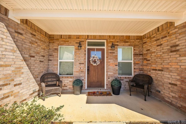 property entrance with covered porch and brick siding