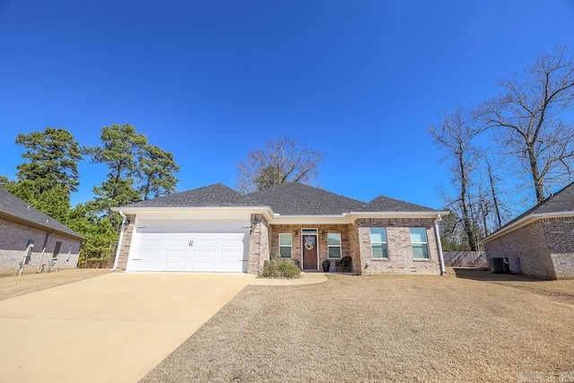 view of front of property with brick siding, a shingled roof, concrete driveway, central AC, and a garage