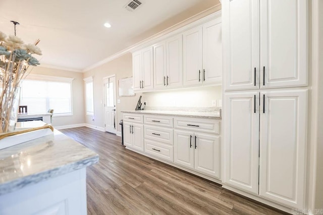 kitchen with visible vents, baseboards, white cabinets, ornamental molding, and light wood finished floors