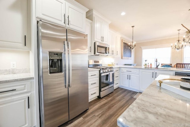 kitchen featuring a sink, white cabinets, appliances with stainless steel finishes, an inviting chandelier, and crown molding