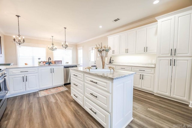 kitchen featuring stainless steel appliances, wood finished floors, white cabinetry, a center island, and crown molding