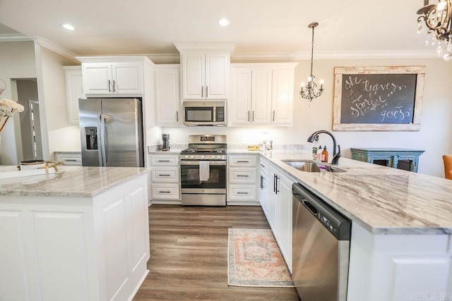 kitchen with appliances with stainless steel finishes, a peninsula, crown molding, a chandelier, and a sink