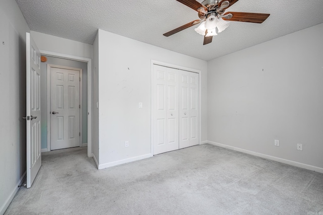 unfurnished bedroom with carpet floors, a textured ceiling, baseboards, and a closet