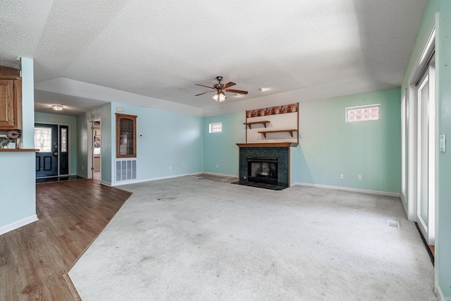 unfurnished living room with a textured ceiling, a tile fireplace, a ceiling fan, and baseboards