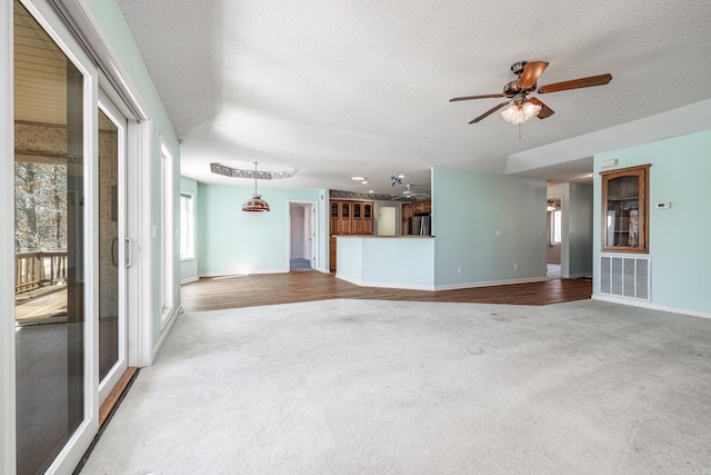 unfurnished living room featuring baseboards, carpet flooring, visible vents, and a textured ceiling