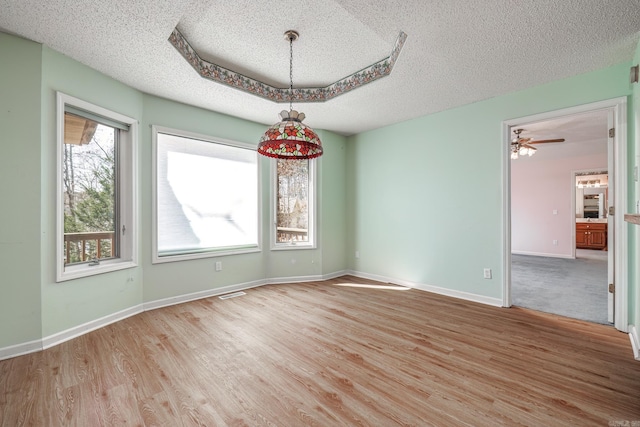 spare room with visible vents, a textured ceiling, baseboards, and wood finished floors