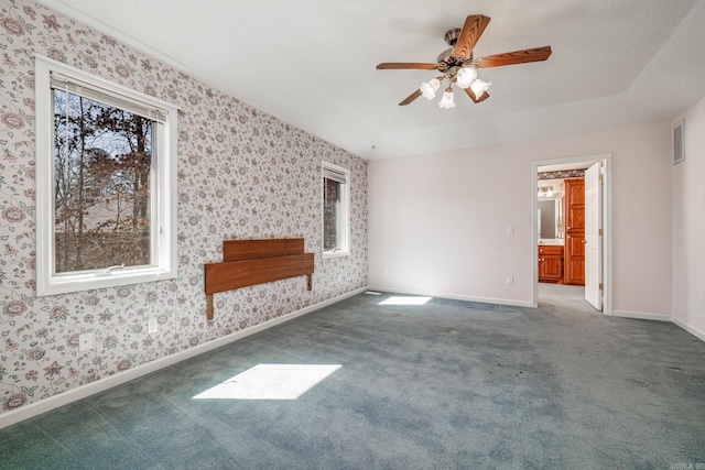 carpeted empty room with wallpapered walls, baseboards, visible vents, and a ceiling fan