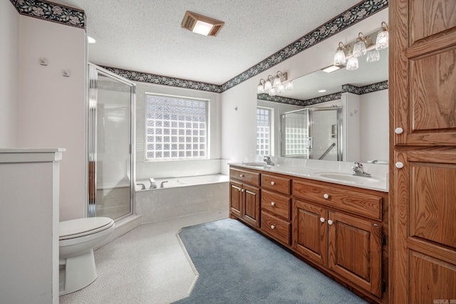 full bath featuring a textured ceiling, double vanity, a sink, and a shower stall