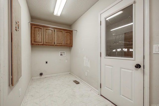 clothes washing area with a textured ceiling, hookup for a washing machine, hookup for an electric dryer, baseboards, and cabinet space