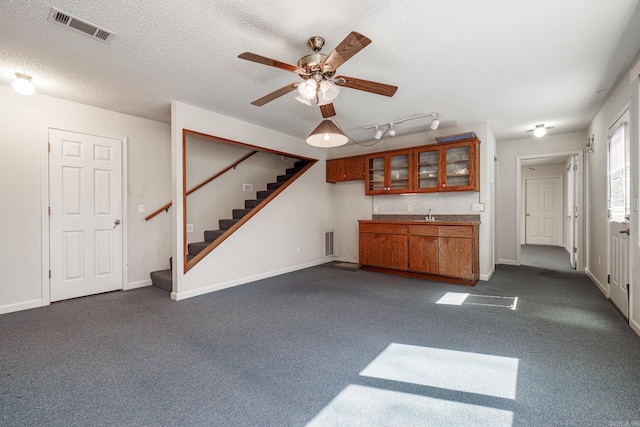 unfurnished living room with baseboards, stairs, visible vents, and a textured ceiling